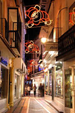 Gece bir şehir merkezi alışveriş caddesi boyunca Festive Christmas Santa süslemeleri, Marbella, İspanya.