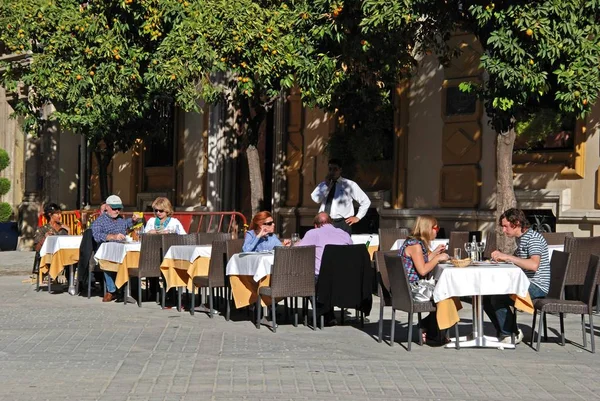 Turistas relajándose en una cafetería en la Plaza Virgen de los Reyes en el centro de Sevilla, España . — Foto de Stock