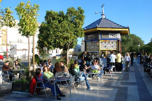 Touristen entspannen sich in einem Straßencafé entlang des Paseo Cristobal Colon im Stadtzentrum von Sevilla, Spanien. — Stockfoto