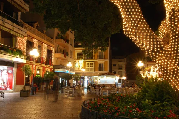 Les gens se relaxent dans un café sur la place de la Constitution la nuit pendant la période de Noël, Fuengirola, Espagne . — Photo