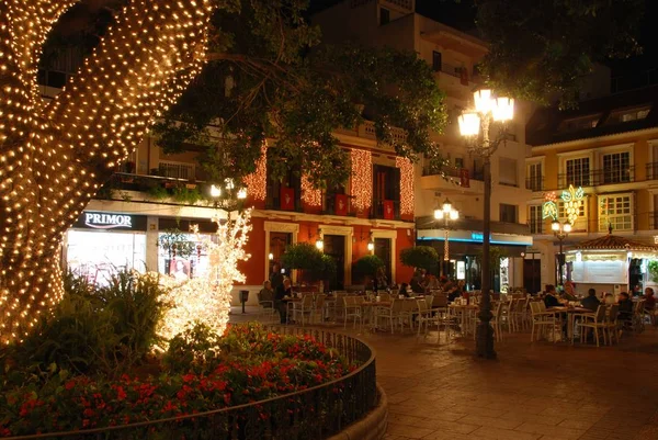 Lidé odpočívácí v pouliční kavárně na ústavě Square v noci během vánočního období, Fuengirola, Španělsko. — Stock fotografie
