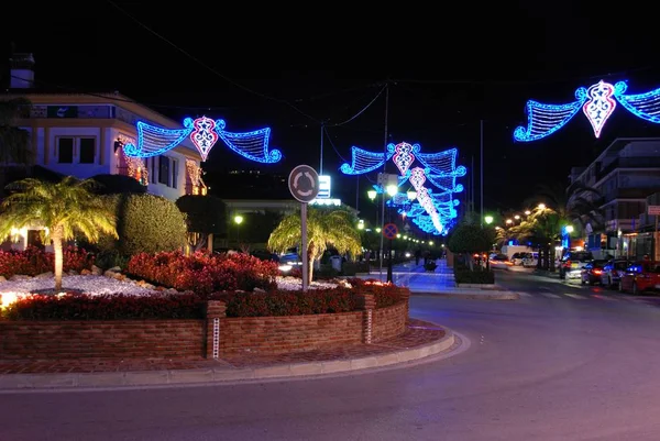 Ulica handlowa centrum miasta na Boże Narodzenie w nocy z wyspą ruchu na pierwszym planie, La Cala de Mijas, Hiszpania. — Zdjęcie stockowe