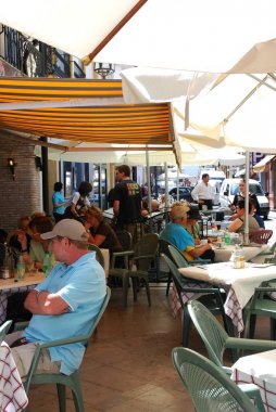 Şehir merkezinde gölgeli bir kaldırım kafede dinlenen turistler, Ronda, İspanya.