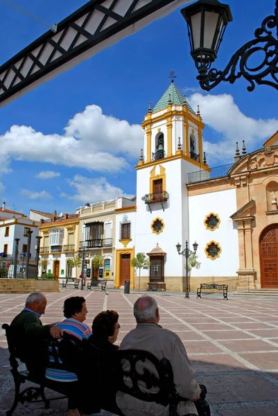 View of the Socorro Parish church in the Plaza del Socorro with people sitting on a bench in the foreground, Ronda, Spain. — Stock Photo, Image