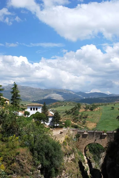 Upphöjd utsikt över den gamla bron korsar ravinen med utsikt mot landsbygden och bergen, Ronda, Spanien. — Stockfoto