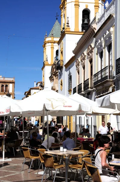 Touristes se relaxant dans les cafés pavés de la Plaza Socorro avec le centre paroissial (centro parroquial) à l'arrière, Ronda, Espagne . — Photo