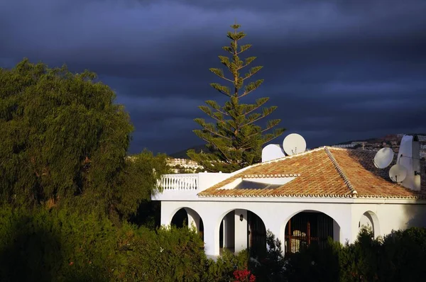 Spanish villa with dark clouds looming to the rear, Calypso, Mijas Costa, Malaga Province, Costa del Sol, Andalucia, Spain, Europe.