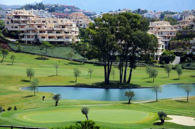 BENAHAVIS, SPAIN - 28 Haziran 2010 - Gölün karşısındaki El Higueral Golf Sahası 'nda arka tarafta daireleri olan Benahavis, İspanya, 28 Haziran 2010