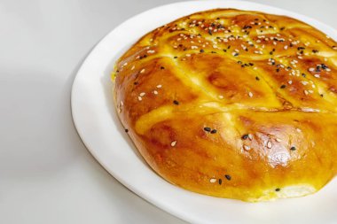 Türk ramazan ekmeği, susam ve siyah tohumile beyaz tabakta pide yakın