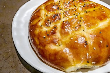 Türk ramazan ekmeği, susam ve siyah tohumile beyaz tabakta pide yakın