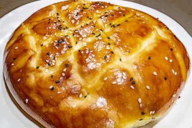 Türk ramazan ekmeği, susam ve siyah tohumile beyaz tabakta pide yakın