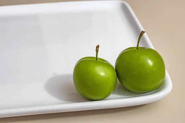close up green plums in white plate
