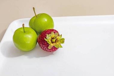 beyaz plaka çilek ile yeşil erik yakın.