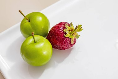beyaz plaka çilek ile yeşil erik yakın.
