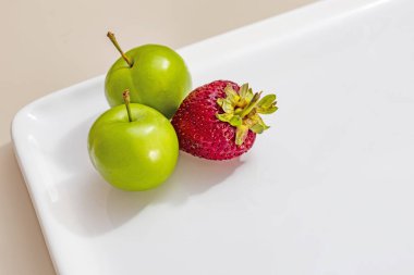 beyaz plaka çilek ile yeşil erik yakın.