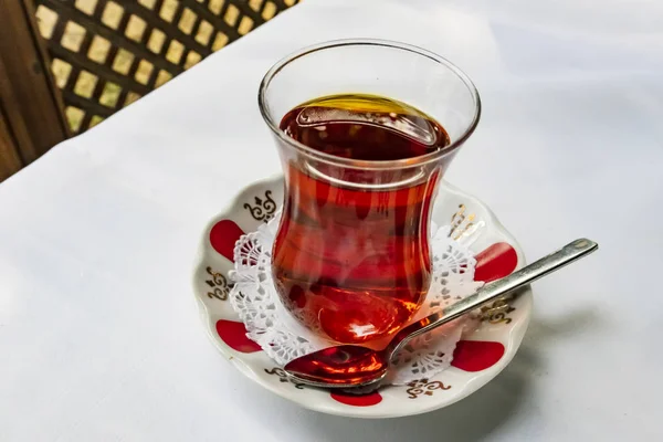 turkish tea in glass cup and patterned little plate on white background