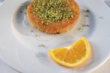 Kunefe, Türk mutfağından tatlı bir peynirli hamur işi. Kadayif eriştesi ve tuzsuz erimiş peynirden yapılır. Fıstıklı ve dilimlenmiş portakal meyveli kunefe yemeye hazır..