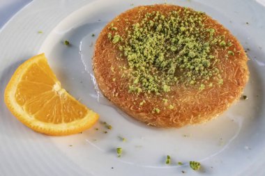 Kunefe, Türk mutfağından tatlı bir peynirli hamur işi. Kadayif eriştesi ve tuzsuz erimiş peynirden yapılır. Fıstıklı ve dilimlenmiş portakal meyveli kunefe yemeye hazır..