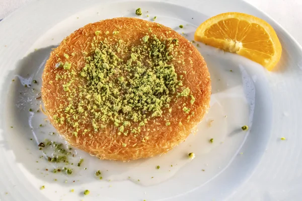 Kunefe, Türk mutfağından tatlı bir peynirli hamur işi. Kadayif eriştesi ve tuzsuz erimiş peynirden yapılır. Fıstıklı ve dilimlenmiş portakal meyveli kunefe yemeye hazır..