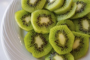 Dilimlenmiş kivi meyvelerini beyaz tabakta kapat