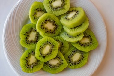 Dilimlenmiş kivi meyvelerini beyaz tabakta kapat