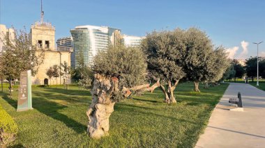 İstanbul, Türkiye. 9 bin 2025. Baruthane parkı. Hyatt Regency İstanbul Atakoy Oteli 'nin çarpıcı modern mimarisine ve şehrin ufuk çizgisine bakan canlı yeşil çimenler ve ağaçların arasından sakin bir park yolu esiyor.. 