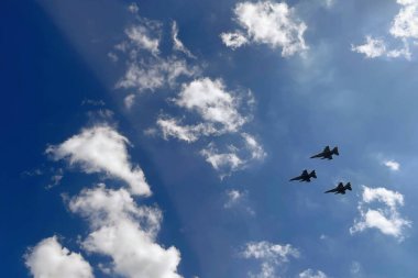 Savaş jetleri düzende. Üç askeri jet mavi gökyüzüne karşı uçuyor. Gücü ve özgürlüğü simgeliyor..