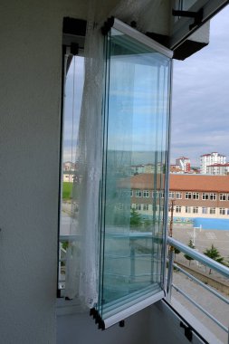 Pencereleri açık cam bir balkon.,
