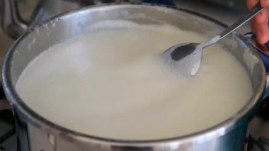 Süt ocakta kaynamaya başlar, bir kadın sütü karıştırır.,