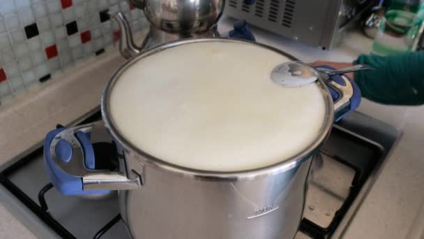 ストーブの上の牛乳が沸騰しオーバーフローし始め 女性はミルクがあふれるのを防ぎました — ストック動画