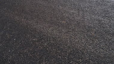 Küçük çakıl taşlarından yapılmış asfalt bir yol asfaltla kaplı.,