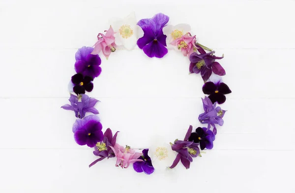 Flowers flat design. Floral round  frame, flowers wreath with   violet , purple, pink white  flowers. Template with copy space on white wooden board. Viola , Aquilegia,  Anemone flowers.