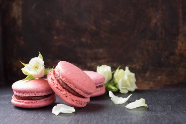 Koyu arkaplanda pembe mercan ve beyaz gül çiçekleri. Fransız kurabiyesi.