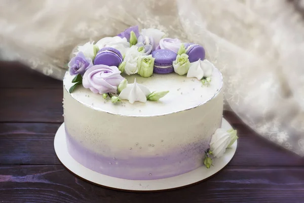 Beautiful cakes. Cake with flowers, purple macaroons and meringues on wooden board. Wedding cake, birthday cake, Mother's day, 8 march, womens day, cake with macaroons