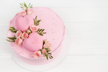 Pembe kek. Kekin üstündeki kalpler pembe güllerle süslenmiş. Düğün konsepti, Sevgililer Günü, Anneler Günü, Doğum günü pastası. Beyaz arkaplan