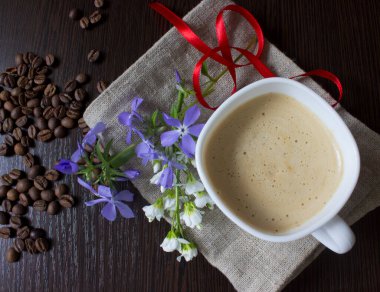 Kahve ve bahar çiçekleri eski ahşap masada, kırmızı kurdele