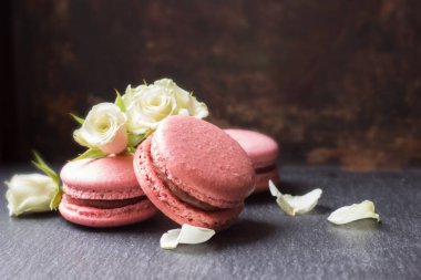 Koyu arkaplanda pembe mercan ve beyaz gül çiçekleri. Fransız kurabiyesi.
