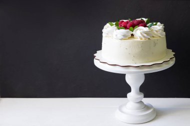 Beyaz standın üzerinde taze ahududu olan lezzetli bir çilekli pasta, siyah arkaplan.