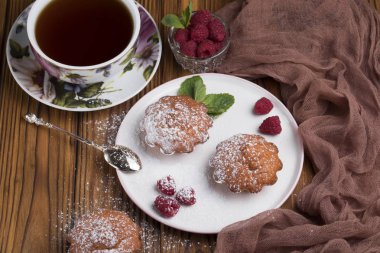 Ahududu ve tabloda çay çaydanlık ile pudra şekeri ile Capcake.