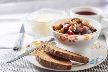 Patlıcan, kırmızı biber ve domates ve kızarmış çavdar ekmeği bir tabakta sebze güveç