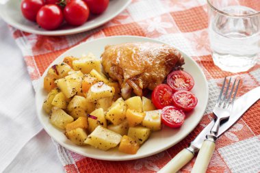 Fırında patates ve bir plaka üzerinde kabak garnitür pişmiş tavuk uyluk