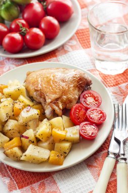 Fırında patates ve bir plaka üzerinde kabak garnitür pişmiş tavuk uyluk