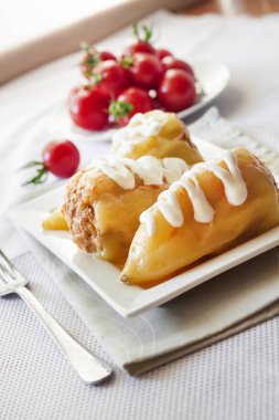 Et ve beyaz bir kare tabak pilav ile doldurulmuş dolmalık biber