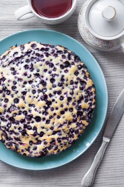 Ev yapımı kek, krepteki mavi plaka ve bir fincan çay içinde belgili tanımlık geçmiş. Üstten görünüm