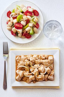 Türkiye güveç domates hardal sos soğan kare plaka ve arka planda renkli domates salatası ile. Üstten görünüm