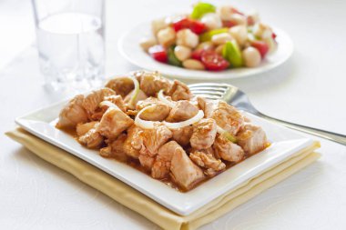 Türkiye güveç domates hardal sos soğan kare plaka ve arka planda renkli domates salatası ile