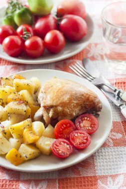 Fırında patates ve bir plaka üzerinde kabak garnitür pişmiş tavuk uyluk