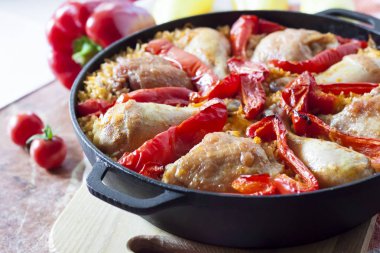 Pirinç ve dökme demir güveç içinde kırmızı dolmalık biber bir yatak üzerinde pişmiş tavuk uyluk ve bacaklar