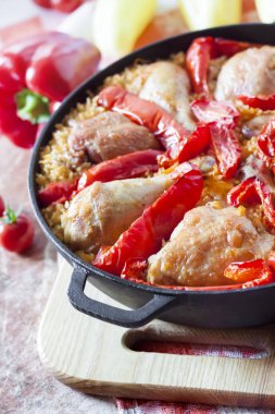 Pirinç ve dökme demir güveç içinde kırmızı dolmalık biber bir yatak üzerinde pişmiş tavuk uyluk ve bacaklar