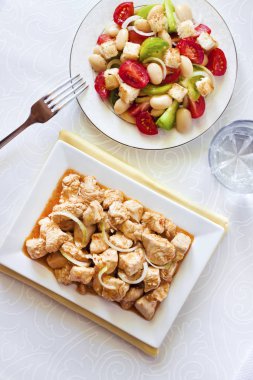 Türkiye güveç domates hardal sos soğan kare plaka ve arka planda renkli domates salatası ile. Üstten görünüm